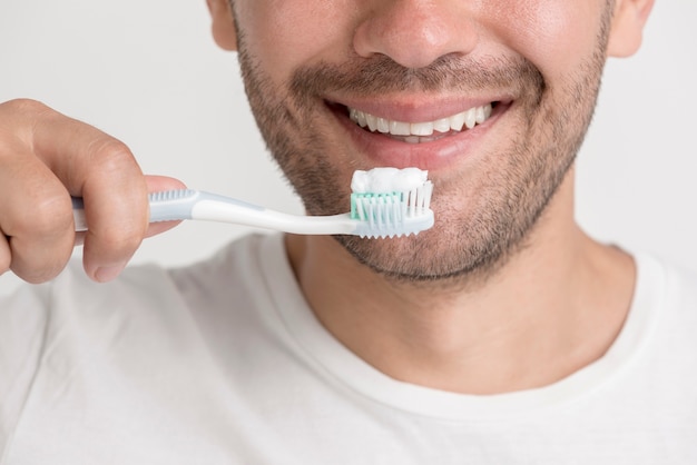 Smiling young man holding tooth brush with paste Free Photo