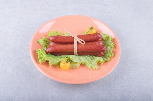 Free Photo | Smoked sausages tied with rope on orange plate.