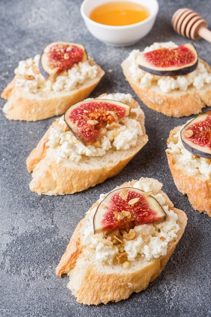 Snacks bruschetta with cottage cheese, walnut and honey and figs Premium Photo