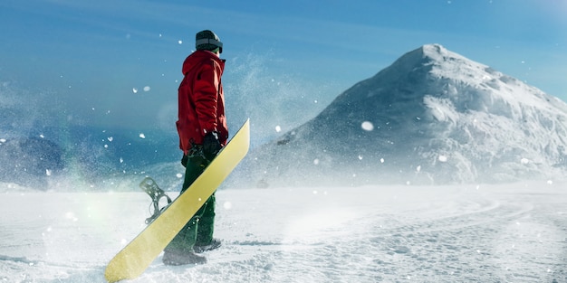 スノーボーダーは手 青い空と雪に覆われた山でボードを保持しています ウィンターアクティブスポーツ エクストリームライフスタイル スノーボード プレミアム写真