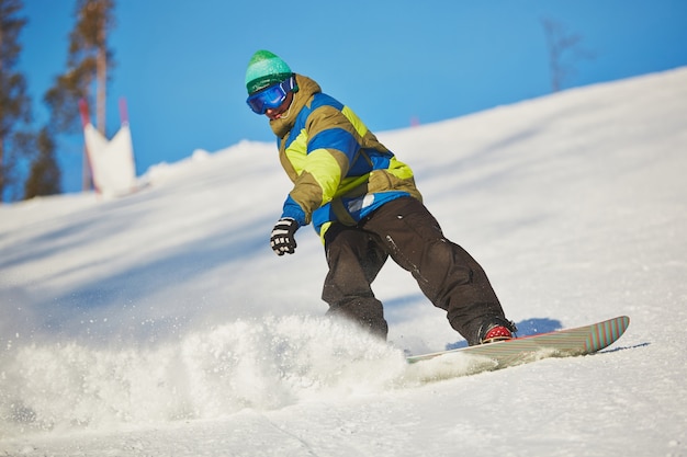 Snowboarder sliding from the mountain in winter day Free Photo