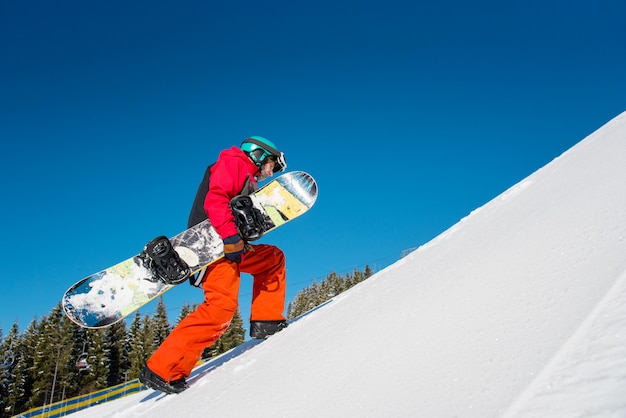 Premium Photo | Snowboarder walking up the slope at winter ski resort