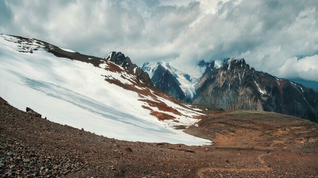 Premium Photo Snowy Mountain Slope Panoramic Alpine Landscape With Snow Capped Mountain Peak And Sharp Rocks Under Dramatic Sky Colorful Sunny Mountain Scenery With Snow Mountain Top