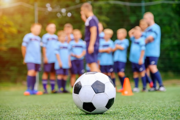フィールド上のコーチとサッカーボールとぼやけた子供サッカーチーム プレミアム写真