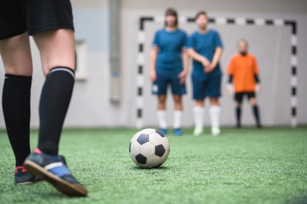 Premium Photo | Soccer ball on green footaball field with legs of young ...