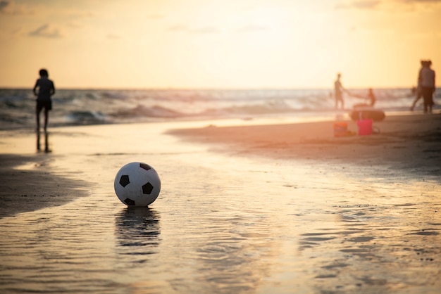 砂の上のサッカーボール ビーチの夕日の海でサッカー プレミアム写真