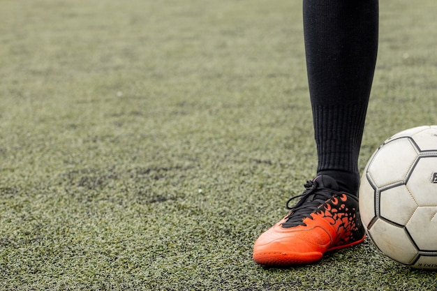 Premium Photo | Soccer ball with his feet on the football field.