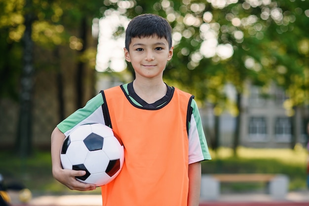 Premium Photo | Soccer player in orange vest holds ball in one hand ...