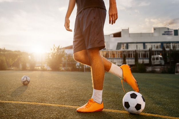 日の出フィールドにボールを持つサッカー選手 屋外スタジアムでのサッカー選手 試合前のトレーニング サッカートレーニング プレミアム写真