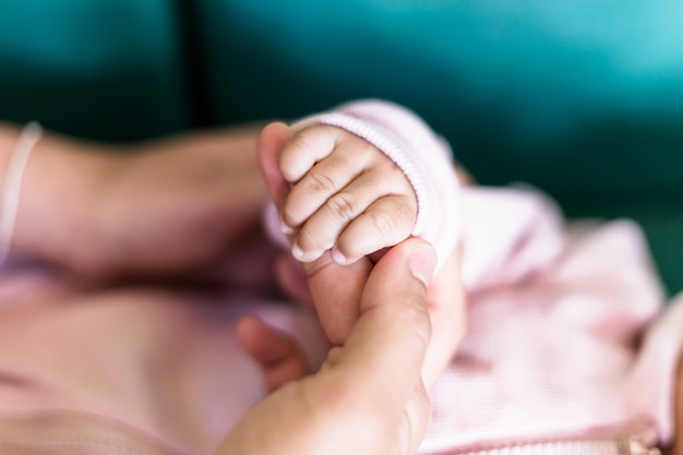 赤ちゃんの手とお母さんのソフトフォーカス 新しい家族と赤ちゃんの保護の概念 大人の指をそっと握る赤ちゃんの手 母親は赤ちゃんの小さな手を握って愛を感じさせる プレミアム写真