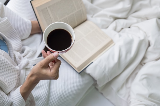 Soft photo of woman on the bed with old book and cup of coffee and copy space. Free Photo