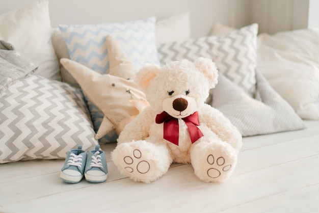ぬいぐるみのクマと青いスニーカー枕のベッドの上の将来の赤ちゃん プレミアム写真