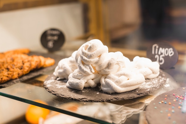 Soft white twisted meringue on slate plate in the display cabinet Free Photo