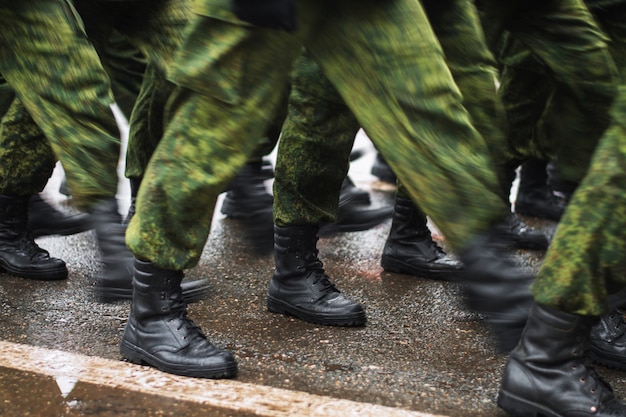 Soldier boots walking on wet asphalt 