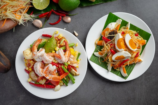 Som tum with corn and shrimp, served with rice noodles and green salad decorated with thai food ingredients. Free Photo