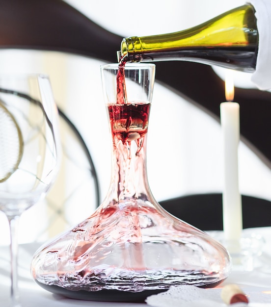 Premium Photo | A sommelier pouring red wine into decanter