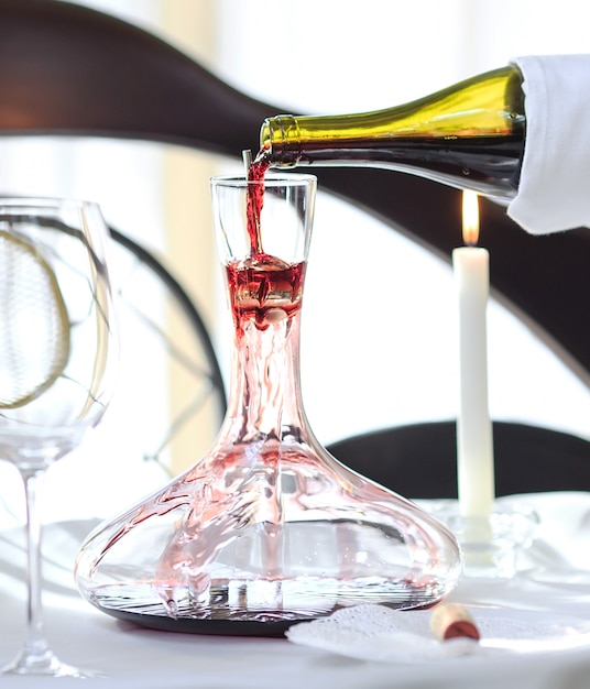 Premium Photo | A sommelier pouring red wine into decanter