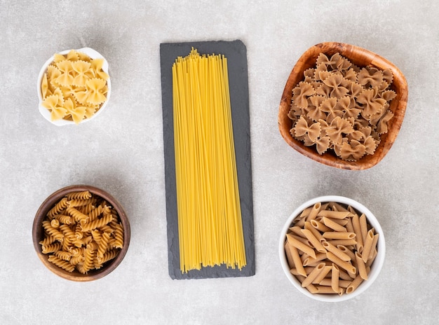 Premium Photo | Spaghetti, farfalle, fusilli and penne pasta over ...