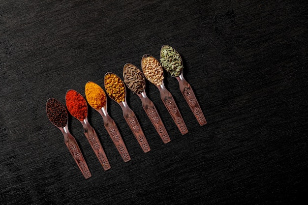 Spices in spoons on black background Premium Photo