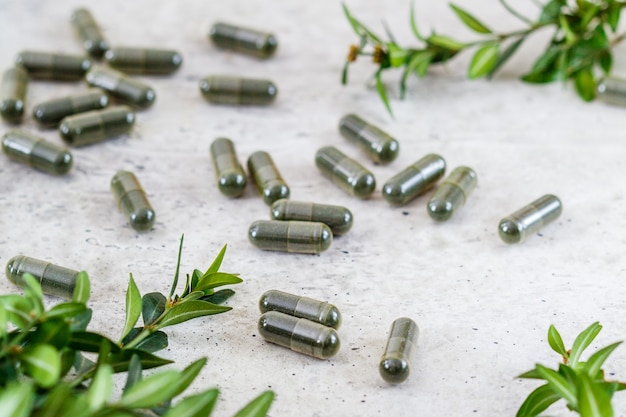 Spirulina or chlorella in capsules on a gray background. wellness concept. Premium Photo