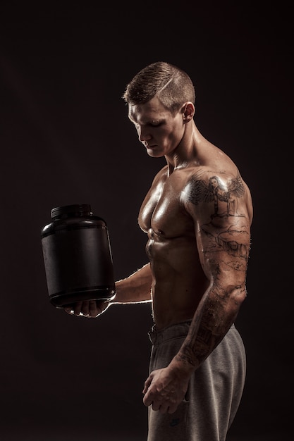 Download Premium Photo Sport Backgrounds Strong Bodybuilder Holding A Plastic Jar With A Dry Protein Isolated Sport Food PSD Mockup Templates