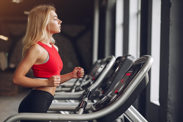 Sports blonde woman in a sportswear training in a gym Free Photo