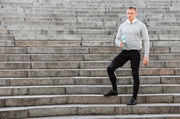 Sporty man holding a bottle of water on stairs Free Photo