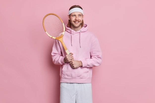 Sporty satisfied active man with mustache holds tennis raquet enjoys playing favorite game during spare time Free Photo