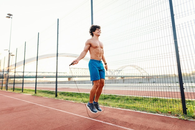 Premium Photo Sporty Smiling Shirtless Man Skipping Rope In Court In