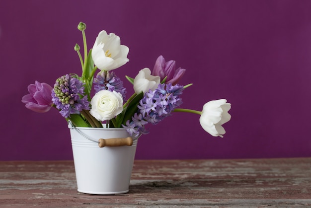 Premium Photo | Spring flowers in bucket on pink background