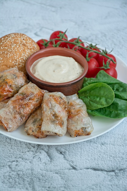 Spring roll with meat and vegetables served on a white dish with sauce Premium Photo