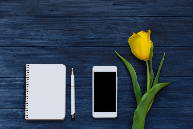 Spring yellow tulips, blank notebook, pen and white smart phone. flat lay, top view. Premium Photo