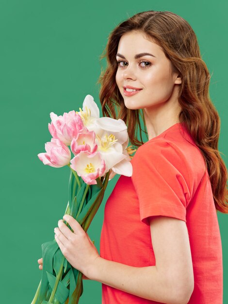 春の色のスタジオの表面に花を持つ美しい少女 女性が花の花束とポーズ プレミアム写真