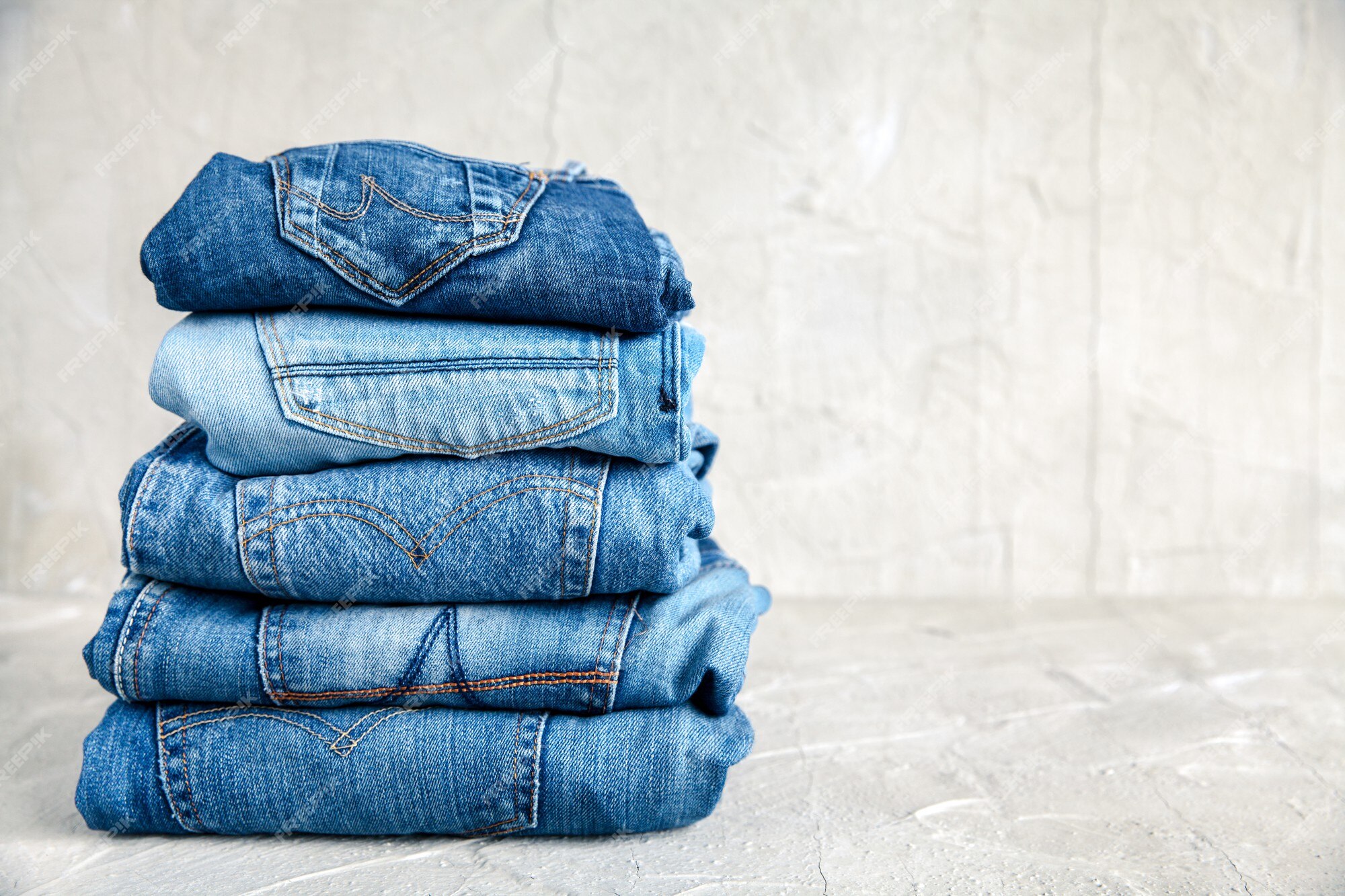 Premium Photo | Stack of blue jeans on a gray background