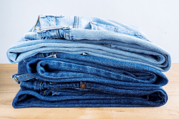 Premium Photo | Stack of blue jeans on wooden table.