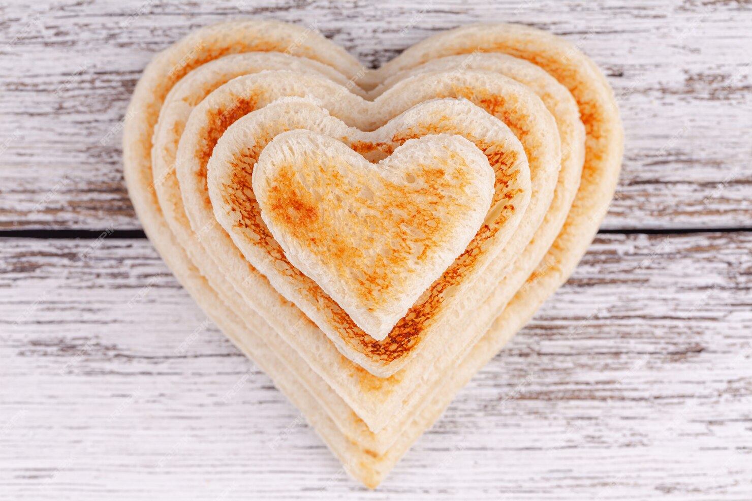 Premium Photo | Stack of toasted bread hearts on wooden table, concept