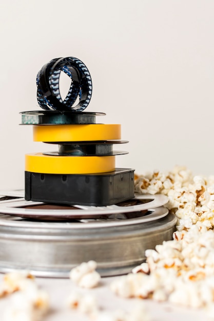 Stacked Of Film Reels With Film Strip Near The Popcorn Against