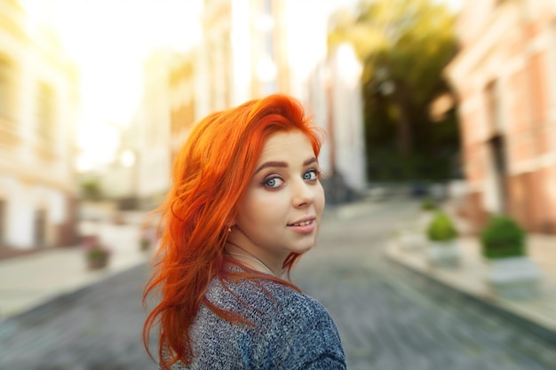 premium photo startled young redhead woman looking back over her shoulder at the camera as she strolls down a deserted urban street https www freepik com profile preagreement getstarted 4865122