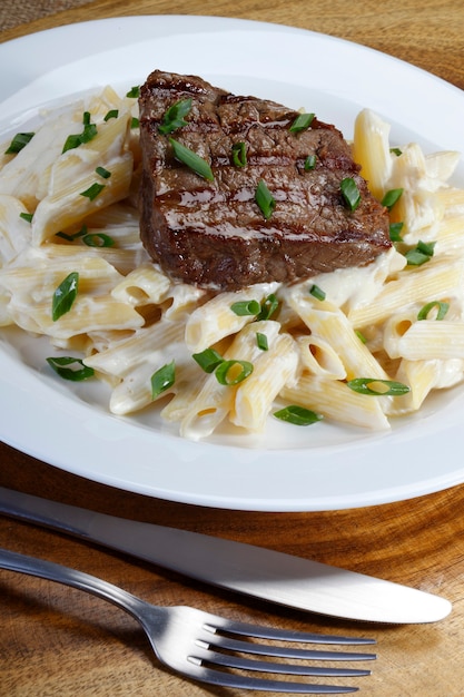 Premium Photo | Steak roasted with penne in white sauce