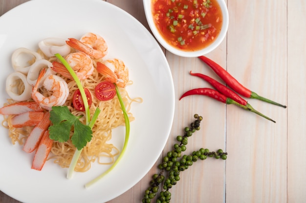 Stir-fried instant noodle with prawn and crab stick along in a white dish. Free Photo