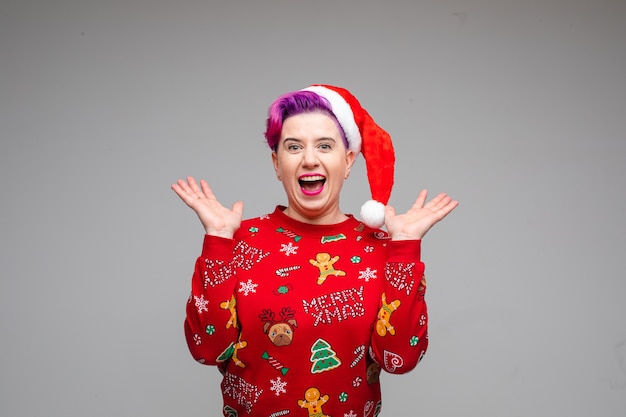 Premium Photo Stock Photo Of Astonished Happy Woman With Dyed Purple Hair Wearing Red Santa Hat And Red Christmas Jersey Holding Arms Half Bent In Excitement