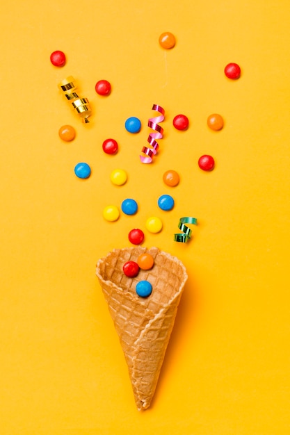 Streamers and gems on waffle against yellow background Free Photo