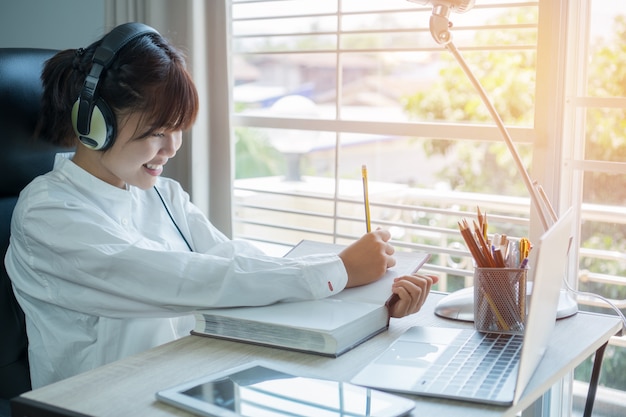 Student learning online study concept: beautiful asian girl listening with headphones and laptop Premium Photo