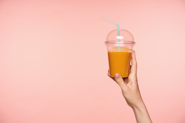 Download Free Photo Studio Photo Of Raised Well Groomed Woman S Hand With Nude Manicure Holding Plastic Cup Of Orange Juice With Straw While Being Isolated Over Pink Background