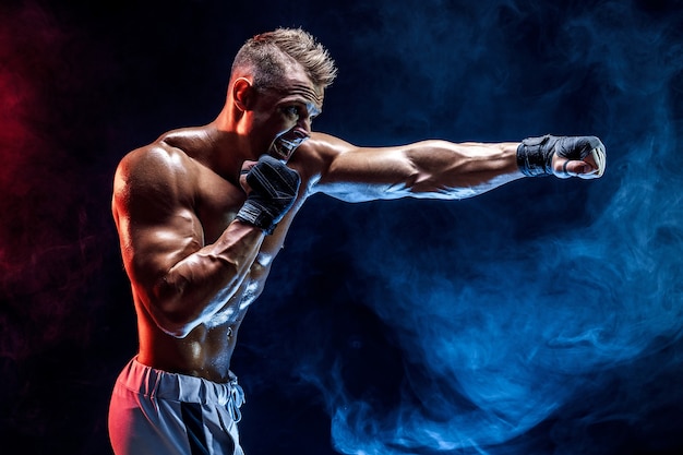 Premium Photo | Studio portrait of fighting muscular man in smoke on dark