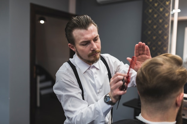 Stylish hairdresser styling hair of man | Free Photo