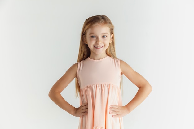 Free Photo Stylish Little Smiling Girl Posing In Dress Isolated On White Wall Caucasian Blonde Female Model Human Emotions Facial Expression Childhood Smiling Holding Hands On A Belt