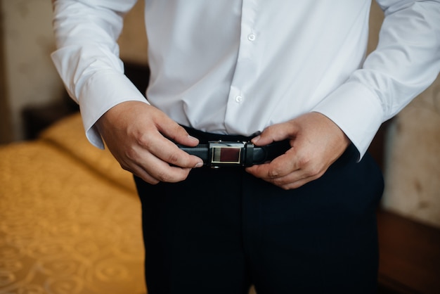 Premium Photo | A stylish man puts on a leather belt