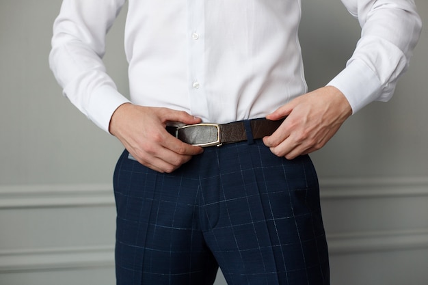 Premium Photo | Stylish man in trousers and a white shirt fastened a ...
