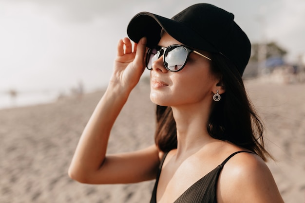 Free Photo Stylish Modern Woman In Trend Outfit Looking On The Ocean With Happy Smile Wearing Cap And Glasses And Enjoys Summer Hot Days Young Caucasian Female Model On The Sea